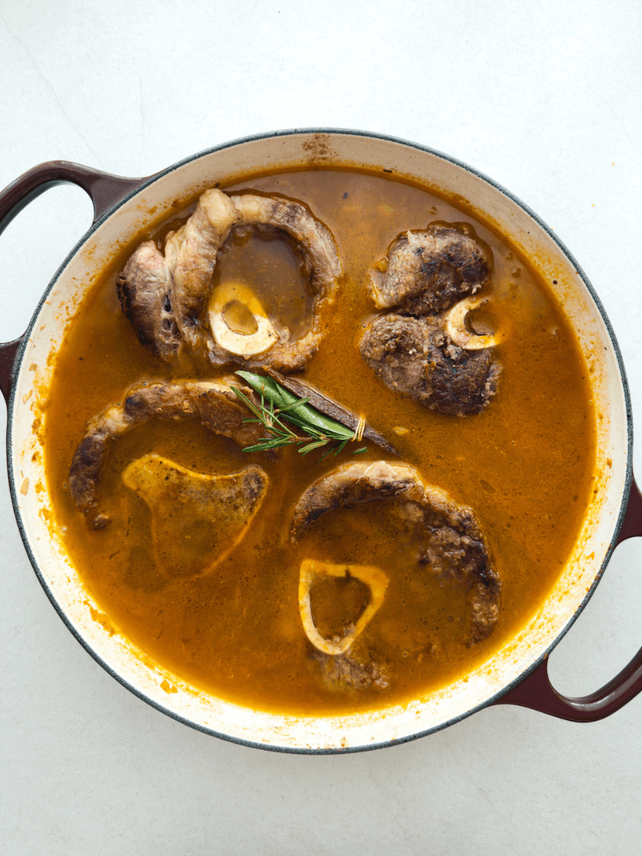 Ossobuco pieces are nestled into a braising liquid, along with a bouquet garni containing rosemary, bay and cinnamon bark. 