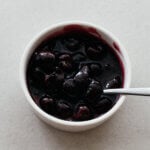 A ramekin filled with a glossy, dark red cherry compote.