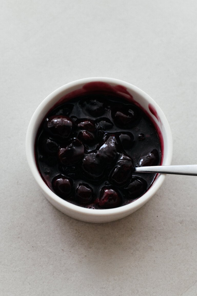 A ramekin filled with a glossy, dark red cherry compote.