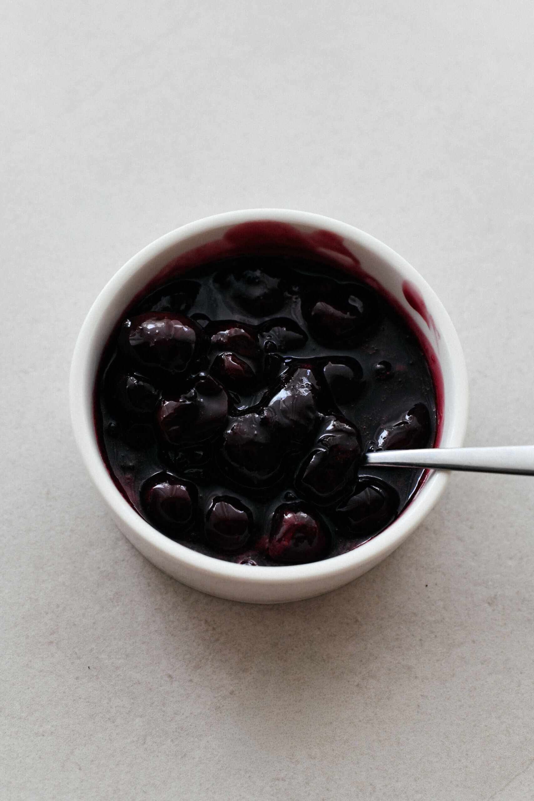 A ramekin filled with a glossy, dark red cherry compote.