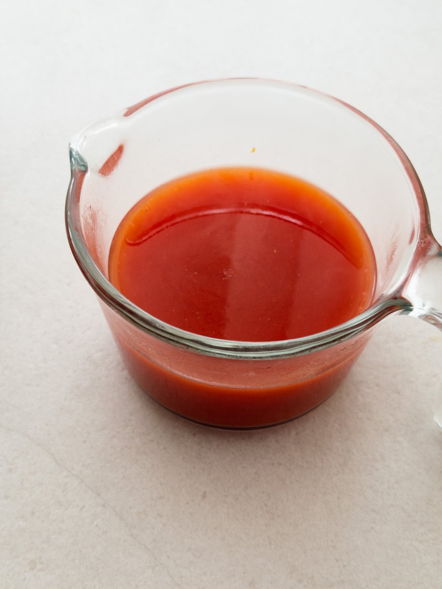 A measuring jug containing a diluted mixture of tomato paste and water. 