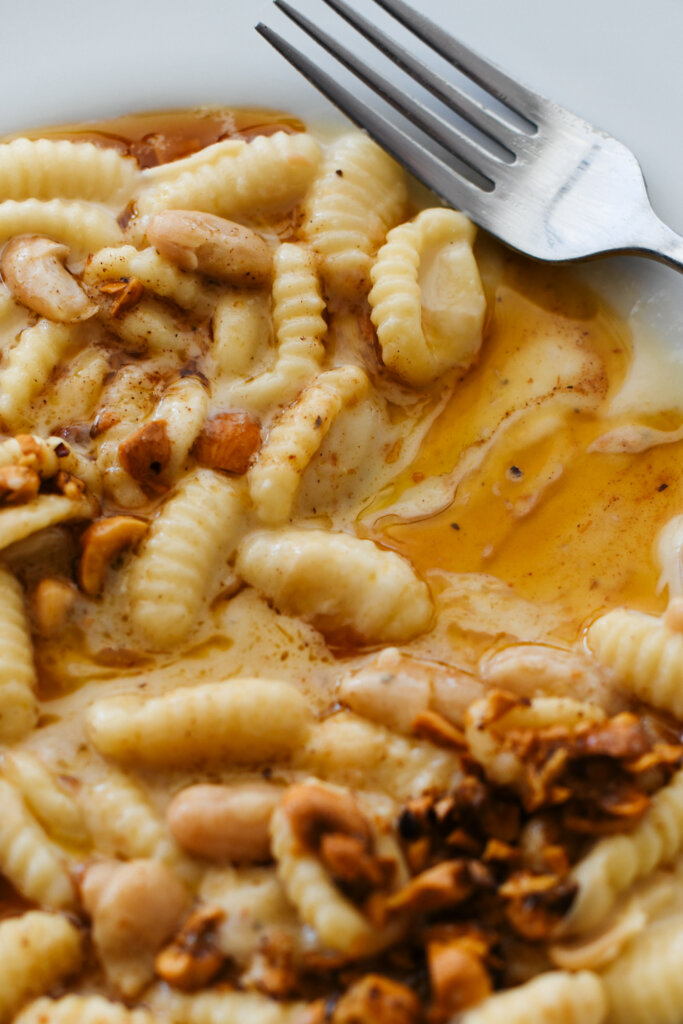 Close-up of cavatelli pasta in a creamy cheese sauce, topped with toasted hazelnuts and drizzled with brown butter