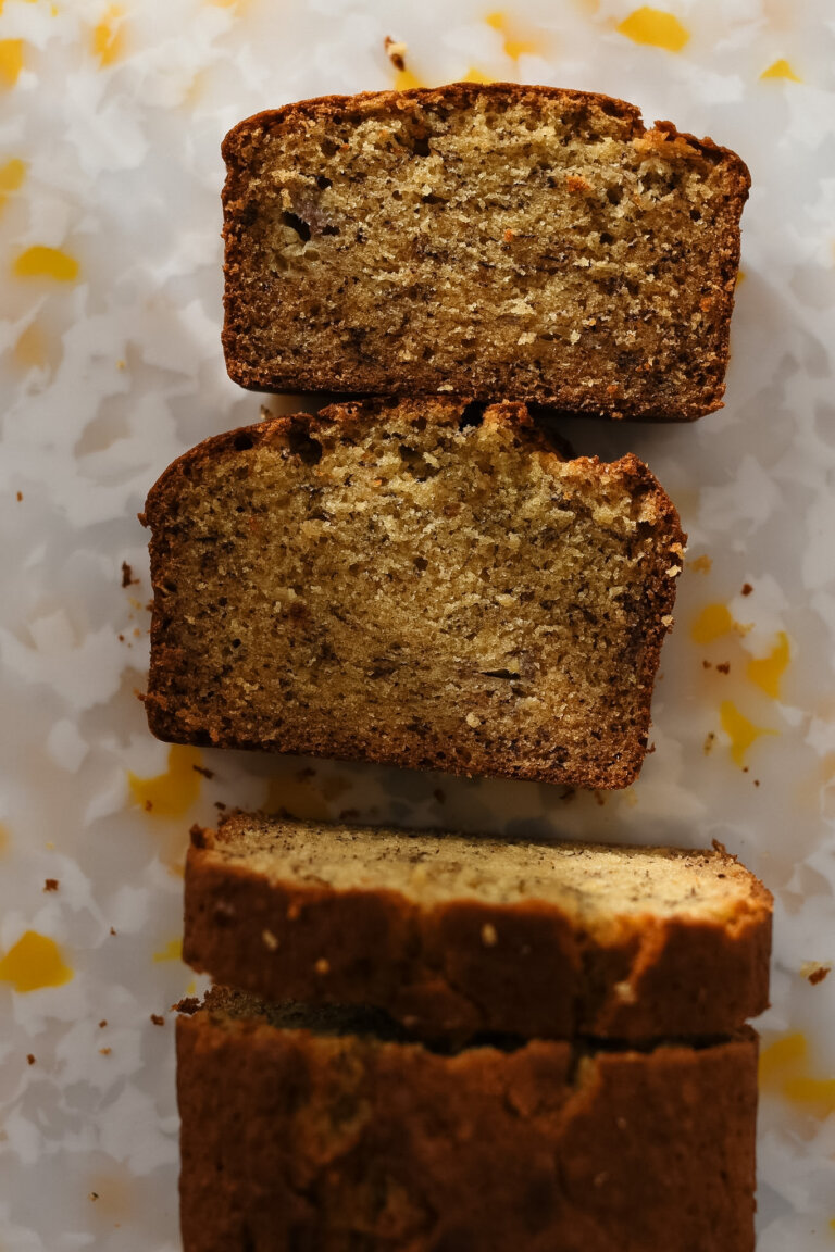 A loaf of brown butter banana bread pictured from above, with a few slices cut out of it lying flat so the crumb is visible.