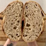 A crumb shot of a loaf of sourdough bread, showing a perfect oval shape with the signature ear.