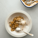 Apple crumble served in a vintage bowl is shown from above, with a scoop of ice cream.
