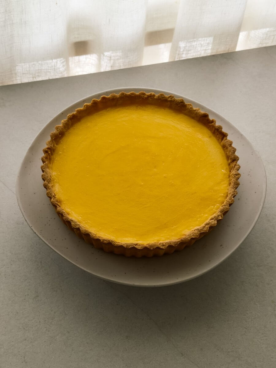 Lemon tart shot from a close angle, pictured on a cake stand.