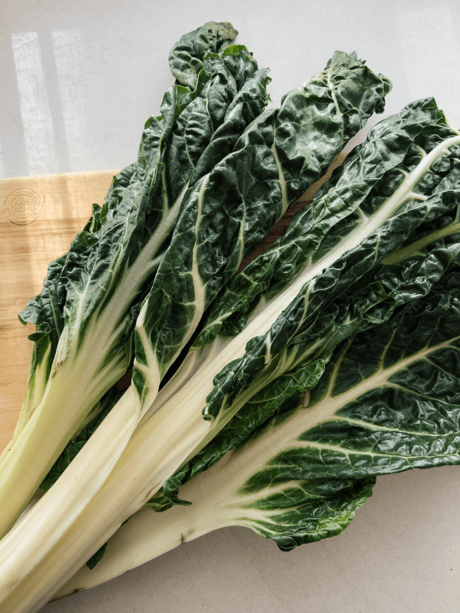 A bunch of fresh silverbeet lies on a chopping board in the afternoon light, perfect for this one pot spanakopita pasta.