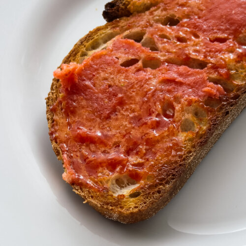 A close up shot of a slice of toasted sourdough slathered in a vibrant pink strawberry butter