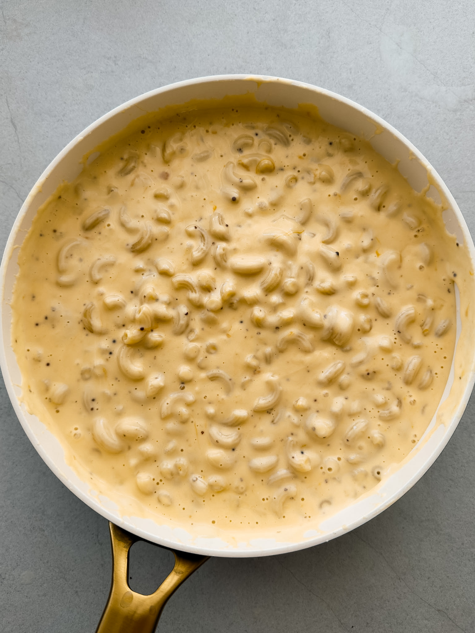 A pot of creamy mac and cheese on a grey bench top. 