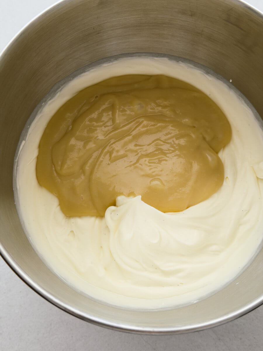 Whipped thickened cream and tahini with condensed milk are combined in a large stainless steel mixing bowl. 