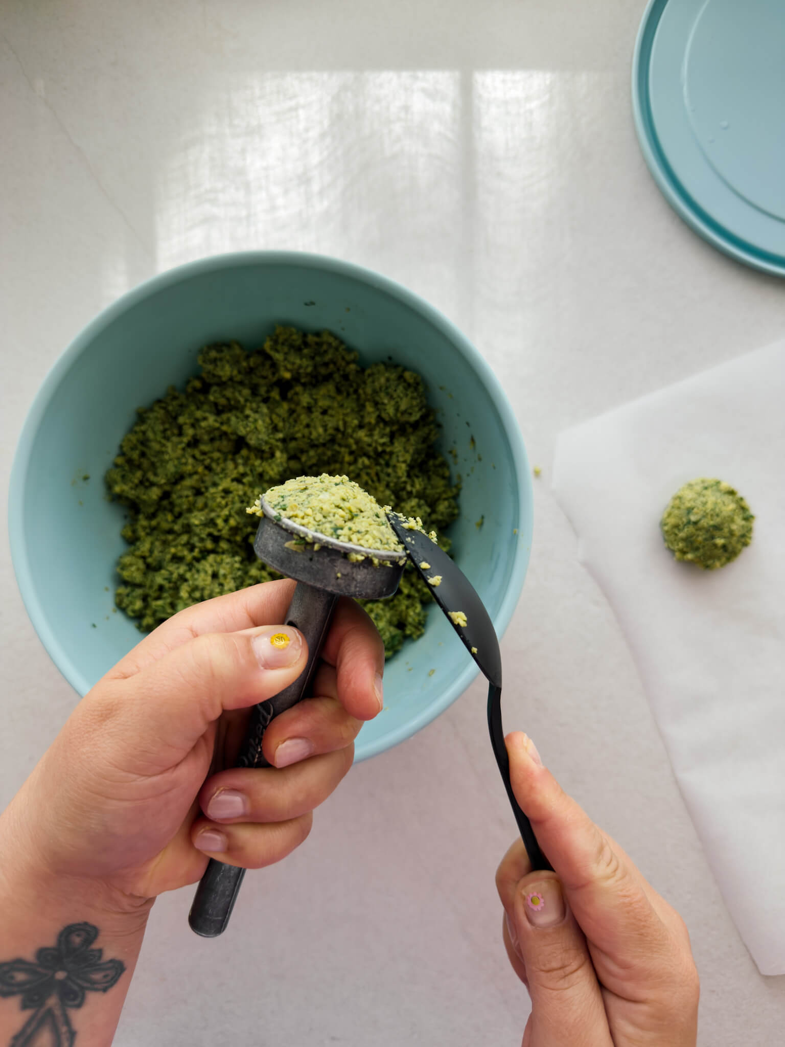Falafel mix being shaped with a traditional falafel press/scoop.