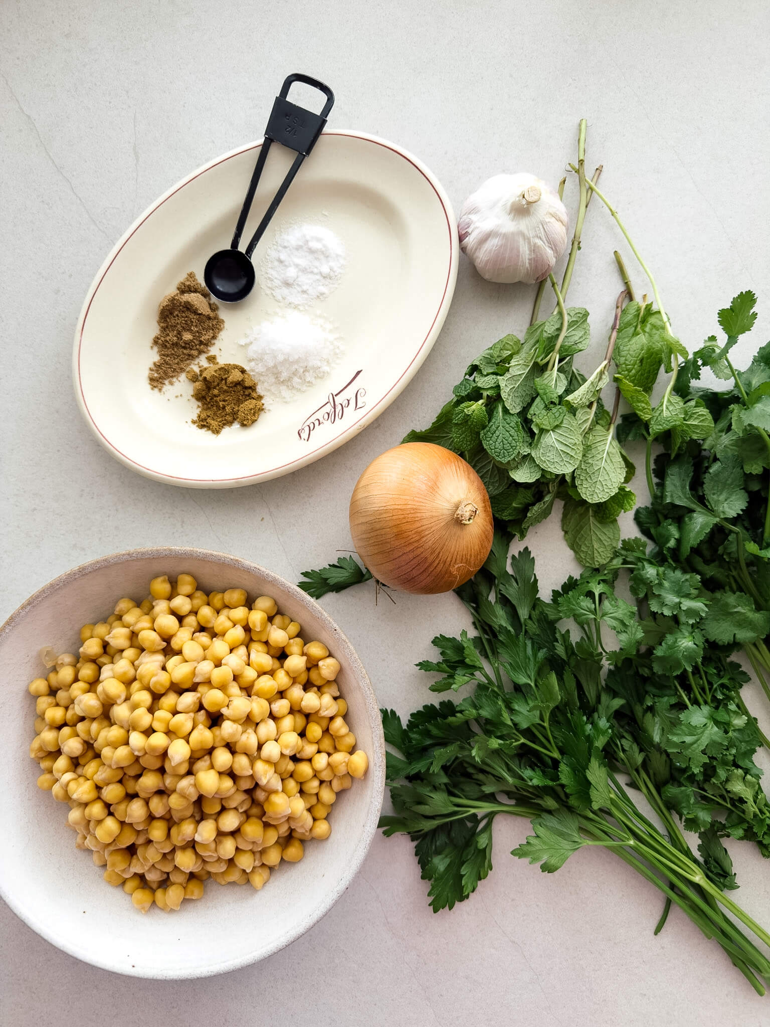 A top down photo of the ingredients needed to make crunchy green herb falafels - soaked chickpeas, herbs and spices. 