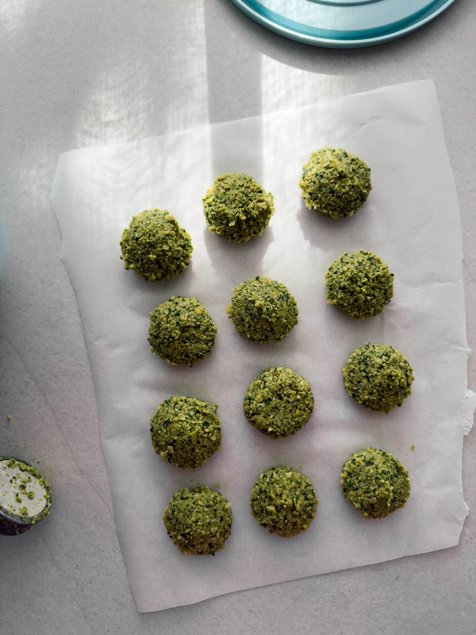 Shaped green herb falafel lined on a piece of parchment paper ready to be fried. 