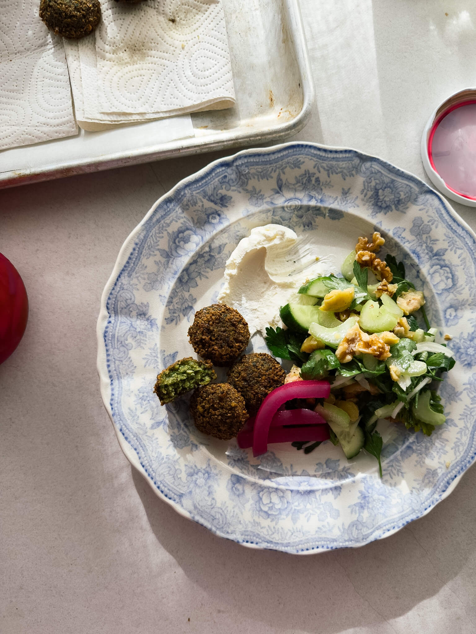A lunch plate with crispy green herb falafel, crunchy salad, fresh labneh and pickled turnips. 