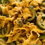 A close up photo of Taiwanese-style knife cut noodles, served in a creamy peanut sauce, with cucumbers, spring onions, coriander and chilli crisp oil.